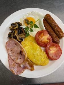 a plate of breakfast food with eggs sausage and mushrooms at The Cottage Inn in Llandeilo