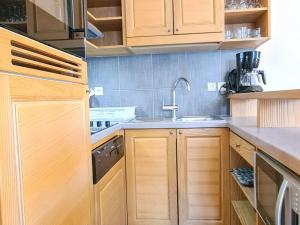 eine Küche mit Holzschränken und einer Spüle in der Unterkunft Appartement spacieux avec accès direct aux pistes, piscine, spa et WIFI – Flaine Montsoleil - FR-1-425-120 in Flaine