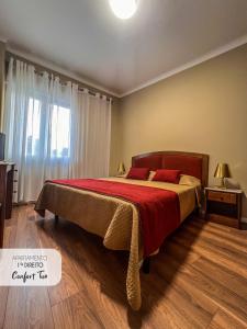 una camera da letto con un grande letto con una coperta rossa di Comfort Tua a Mirandela