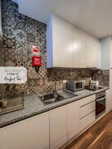 a kitchen with white cabinets and a sink at Comfort Tua in Mirandela