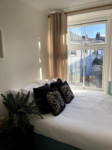 een bed met kussens in een kamer met een raam bij 3-Bed Luxe Truro Townhouse Gem. Escape in Style! in Truro