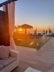 sala de estar con sofá en un balcón con vistas a la puesta de sol en Apartamento con piscina en el Paseo Cruz del Mar, en Chipiona