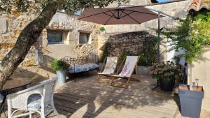 un patio con 2 sillas y una sombrilla en Au creux des vignes, en Les Verchers-sur-Layon