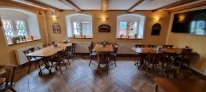 a restaurant with wooden tables and chairs and windows at Restaurant & Pension Liebenstein in Libá