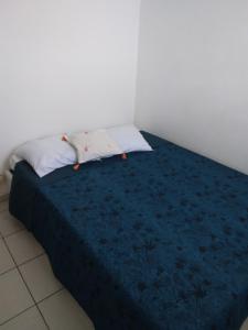 Bett mit blauer Bettdecke und 2 Kissen in der Unterkunft LES BOUGAINVILLIERS in Le Gosier