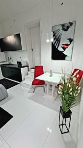 a white living room with a white table and red chairs at Airport Luxury Apartman 42 in Vecsés