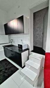 cocina con armarios blancos y negros y sofá rojo en Airport Luxury Apartman 42, en Vecsés