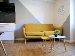 sala de estar con sofá amarillo y mesa en Appartement moderne entièrement rénové en Aurillac