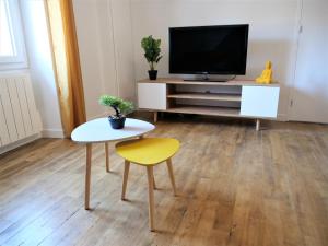 uma sala de estar com uma televisão, uma mesa e um banco amarelo em Appartement moderne entièrement rénové em Aurillac