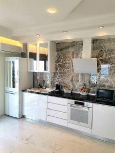 a kitchen with white appliances and a stone wall at Lux Suite Sea Front Avra in Pefkohori