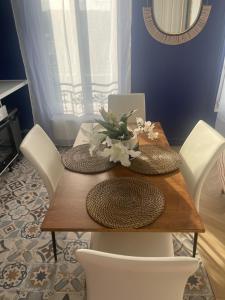 a dining room table with white chairs and a table with flowers on it at L'AMAZONIE - Lovely apartment near to the train station and Orly Airport in Juvisy-sur-Orge