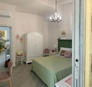 een slaapkamer met een groen bed en een kroonluchter bij Il Fiore Bianco in Capo dʼOrlando