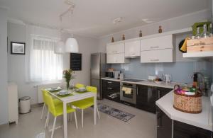 cocina con mesa pequeña y sillas amarillas en Sunny home near BUD with 2BR, AC and free parking, en Vecsés