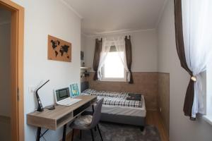 Dormitorio pequeño con escritorio, cama y ordenador en Sunny home near BUD with 2BR, AC and free parking en Vecsés