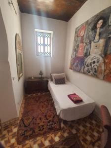 a bedroom with a bed and a painting on the wall at The Jewel of the Northern Moroccan Atlantic in Asilah in Asilah