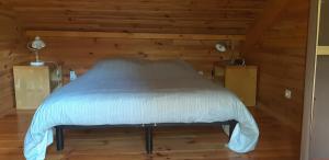 Cama en habitación con paredes de madera en la cabane au fond du jardin, en Arsac