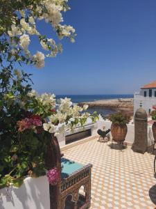 a patio with flowers and a table and a view of the ocean at The Jewel of the Northern Moroccan Atlantic in Asilah in Asilah
