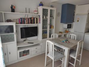 a kitchen with a table with a television and a white cabinet at Apartamento con piscina en primera linea de playa in Puerto de Mazarrón