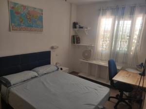 een slaapkamer met een bed, een bureau en een raam bij Apartamento con piscina en primera linea de playa in Puerto de Mazarrón