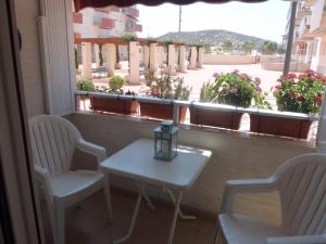 een tafel en 2 stoelen op een balkon met een raam bij Apartamento con piscina en primera linea de playa in Puerto de Mazarrón