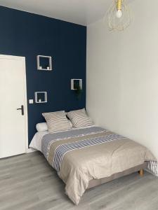 1 dormitorio con 1 cama grande y pared azul en Appartement Centre ville Louviers, en Louviers