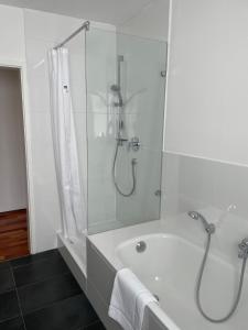 y baño blanco con ducha y bañera. en Skyblue, en Friedrichshafen