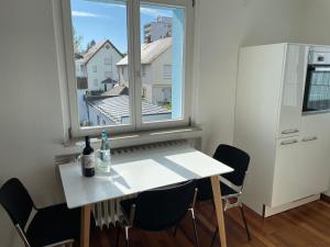 una mesa y sillas blancas en una habitación con ventana en Skyblue, en Friedrichshafen