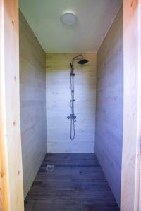 a shower in a room with a wooden wall at Imanje Lotus Garden in Šabac