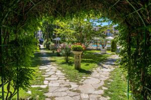 einen Garten mit einem Bogen und einem Blumentopf darauf in der Unterkunft Hotel Riva - All Inclusive in Sonnenstrand