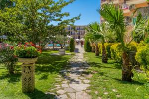 una pasarela a través de un parque con flores y palmeras en Hotel Riva - All Inclusive, en Sunny Beach