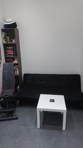 um sofá preto com uma mesa de centro branca num quarto em * Moulin Rouge Getaway * 1BR + Desk + Gym weights em Paris
