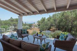 eine Terrasse mit einem Sofa, Stühlen und einem Tisch in der Unterkunft Villa Helonaki in Kassiopi