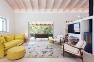 ein Wohnzimmer mit einem gelben Sofa und einem TV in der Unterkunft Villa Helonaki in Kassiopi