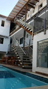 a swimming pool with a staircase next to a building at Pousada Caravela in Arraial do Cabo