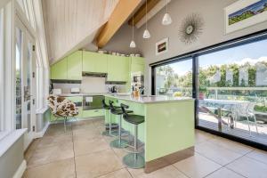 una cucina con armadi verdi e un bancone con sgabelli di Clonaslee House a Coleraine