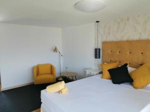 a bedroom with a white bed and a yellow chair at Chabela's water wall in La Lajita