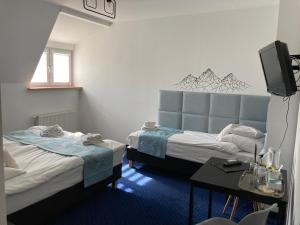 um quarto com duas camas e uma televisão em Hotel Bella em Jelenia Góra
