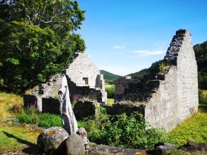 una vieja pared de piedra con una estatua delante de ella en Craskie Glamping Pods en Inverness