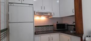 La cuisine est équipée de placards blancs et d'un réfrigérateur blanc. dans l'établissement APARTAMENTO EN CORRALEJO, à Corralejo
