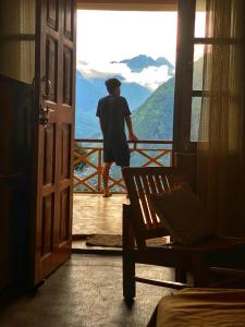 un hombre parado en un balcón mirando a una montaña en Pine Tower Inn, en Manali