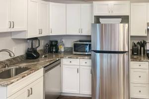 a kitchen with white cabinets and a stainless steel refrigerator at Cozy Modern Apt in the Heart of Fells Point! in Baltimore