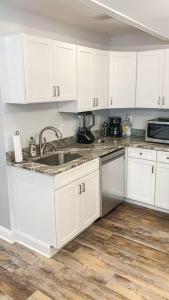 a kitchen with white cabinets and a sink at Cozy Modern Apt in the Heart of Fells Point! in Baltimore
