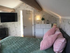 um quarto com uma cama com almofadas cor-de-rosa e uma televisão em Mysigt HÄRBRE STUGA med utsikt över Siljan em Rättvik