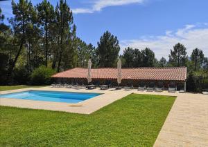 a swimming pool with chairs and a building at Quinta dos Morangueiros in Armamar