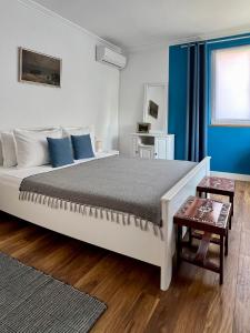 a bedroom with a large white bed with blue walls at Fos and Flame in Sozopol