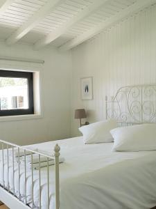 a white bed with white pillows and a window at Quinta dos Morangueiros in Armamar