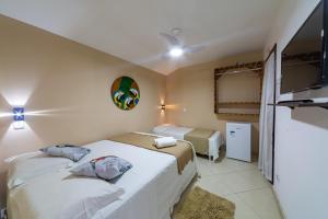 a hotel room with two beds and a tv at Praia do Forte Suites in Praia do Forte