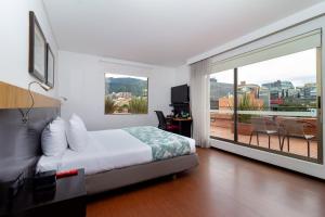 a hotel room with a bed and a large window at Hotel Madisson Inn Luxury By GEH Suites in Bogotá