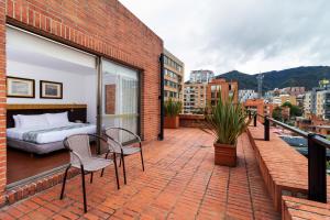 uma varanda com uma cama e cadeiras num edifício de tijolos em Hotel Madisson Inn Luxury By GEH Suites em Bogotá