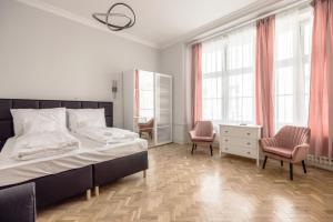 a bedroom with a large bed and two pink chairs at Prime Star Fashion street modern luxury apartments in Budapest